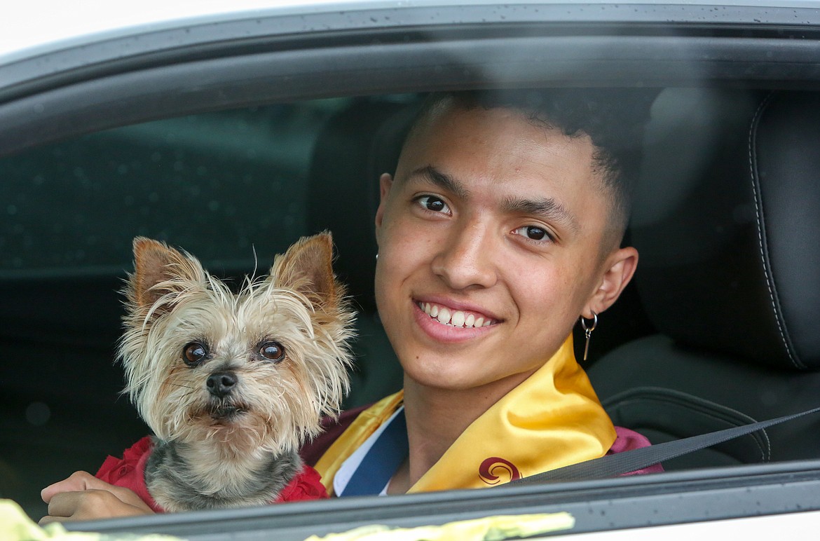 Angel Tapia poses for a photo with his dog from inside his car as he pulls into the Grant County Fairgrounds on Friday afternoon for the Moses Lake High School 2021 graduation parade ceremony.