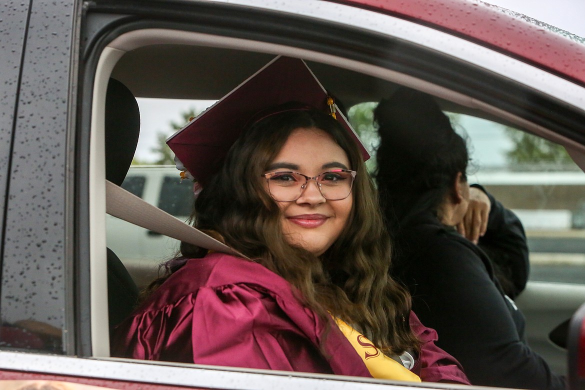 Moses Lake High School graduate Rylee Mcknight avoids the rain from inside her vehicle while waiting for the graduation parade ceremony to kick off at the Grant County Fairgrounds on Friday, June 11.