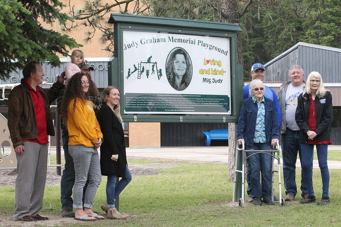 Members of the Graham family gather around the sign indicating the Graham Memorial Playground at the Libby Elementary School. Friends and family of the former elementary school teacher dedicated the playground in memory of Judy Graham on June 12. (Will Langhorne/The Western News)