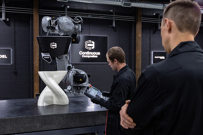 Sam VanDenBerg, left, and Tyler Wilson demonstrate Continuous Composites' capabilities of patented Continuous Fiber 3D Printing process and technology. The Coeur d'Alene company was recently awarded a $750,000 Phase II Small Business Innovation Research contract from the Department of Defense.