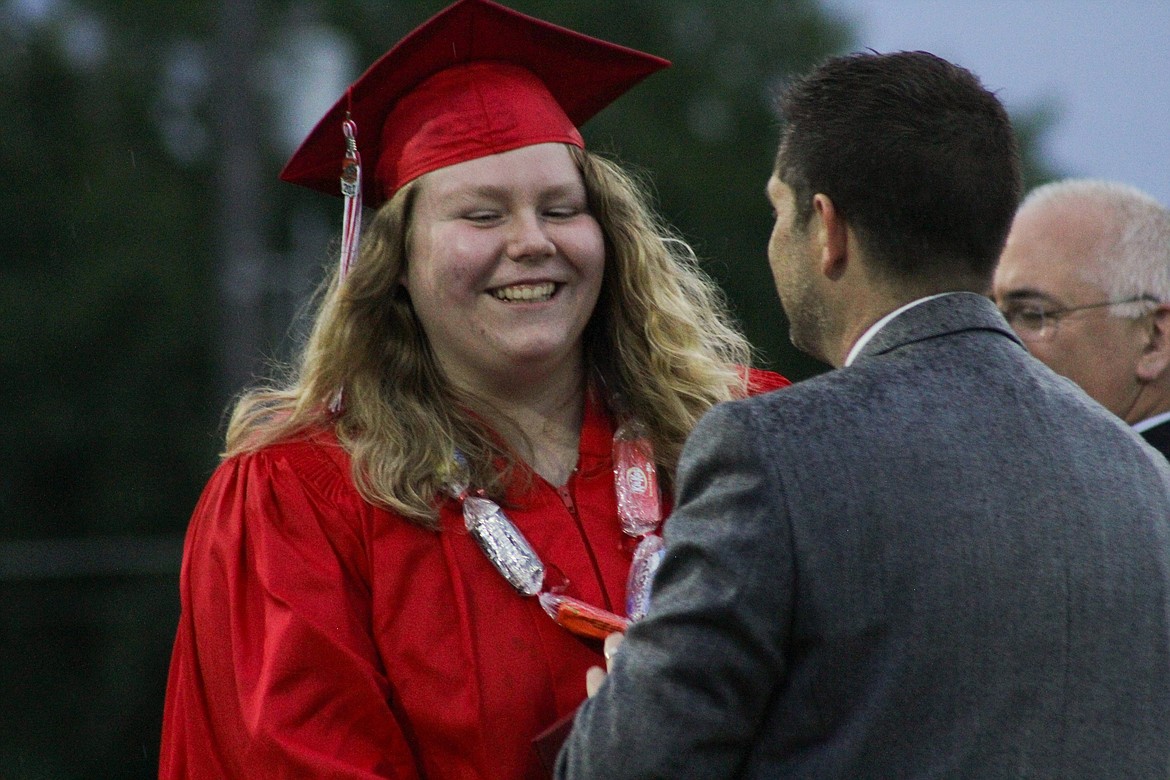 A graduate shakes Principal David Miles' hand as she receives her diploma Friday at War Memorial Field.