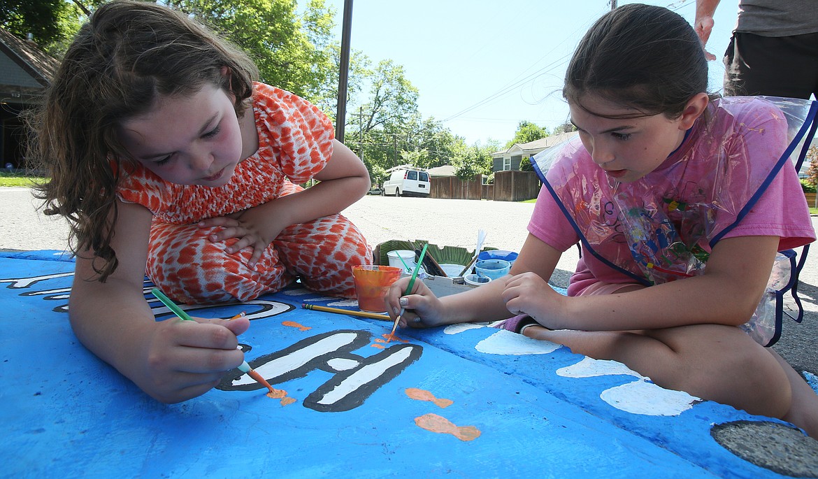 Francesca Drake, left, and Madeleine O'Dowd add goldfish to the "H20nly" storm drain mural on the southwest corner of Ninth Street and Coeur d'Alene Avenue at Sorensen Magnet School on Monday.