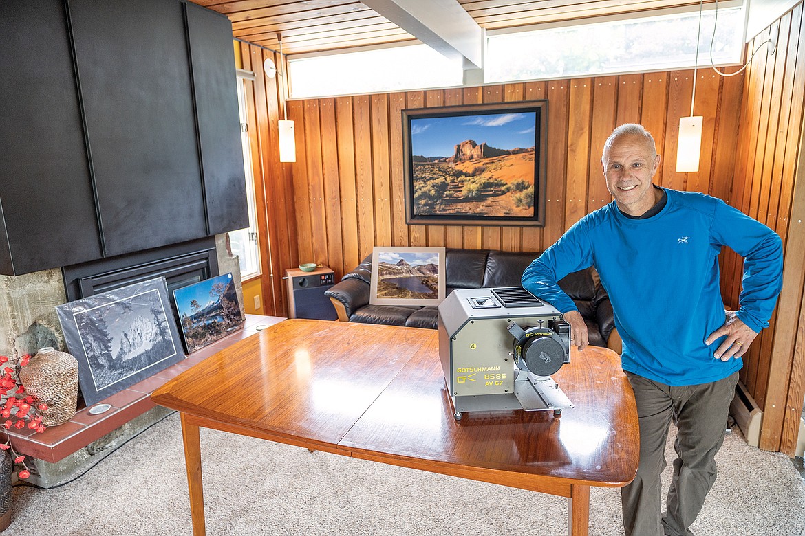 Local historian Arne Boveng with a large format projector at his home. He will be showing a collection of Ed Gilliland photos in an August event at the Northwest Montana History Museum. Behind him is some of Gilliland's work.