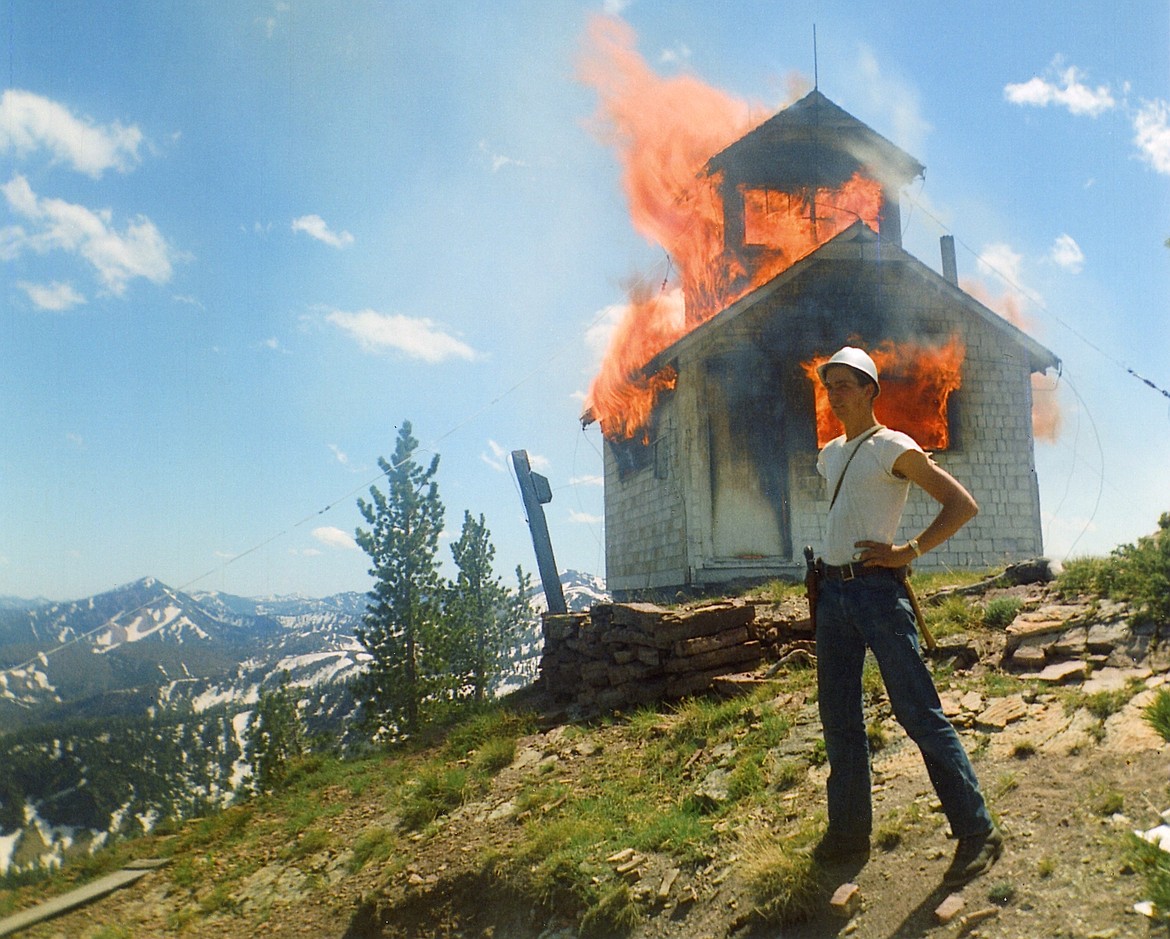 Hank Mader stands in front of an unidentified abandoned lookout as he burns it for the National Forest Service in this undated photo. (photo courtesy of the Northwest Montana Lookout Association)
