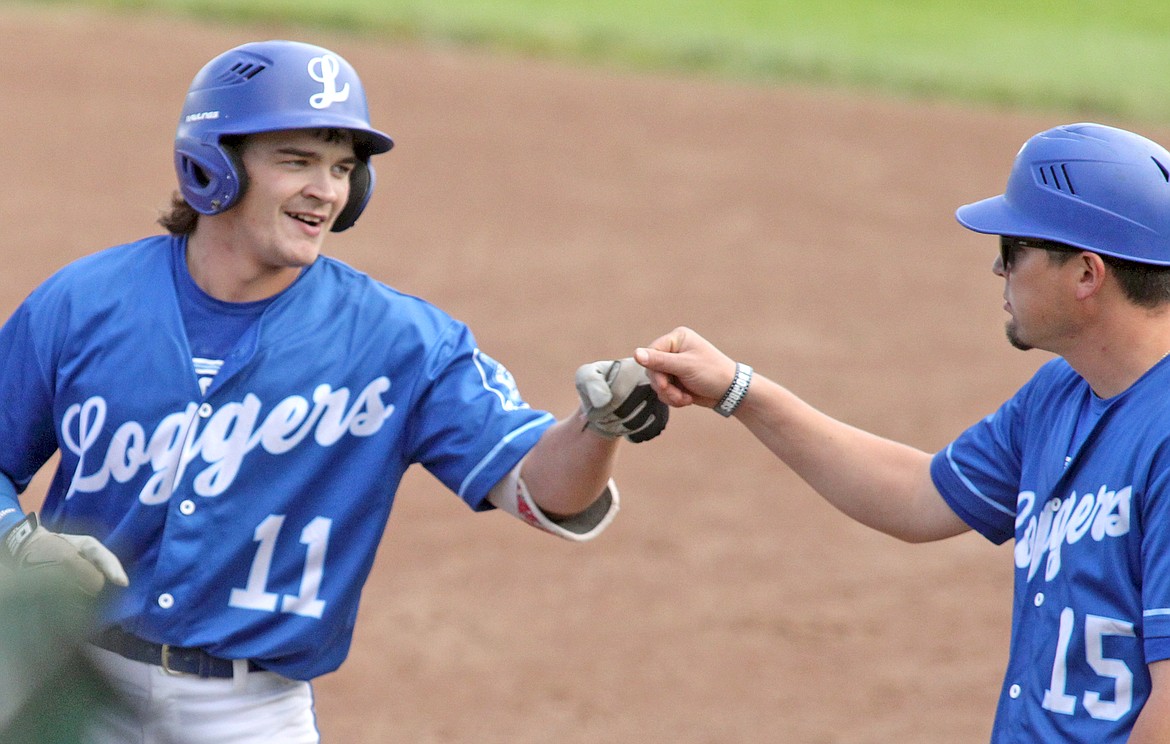 A base hit on the 1-2 pitch for Hunter Hoover earns him a celebratory fist bump with first base coach Joe Flores Tuesday evening during the Libby Loggers' matchup with the Bitterroot Red Sox. (Paul Sievers/The Western News)