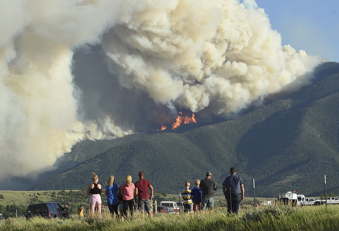 Residents watch as flames from the Robertson Draw fire burn above Red Lodge, Mont., Tuesday evening, June 15, 2021. Wildfires burning in Montana exploded in size over the past 24 hours and triggered evacuations of people from rural areas as scorching heat and heavy winds stoked the blazes. (Larry Mayer/The Billings Gazette via AP)