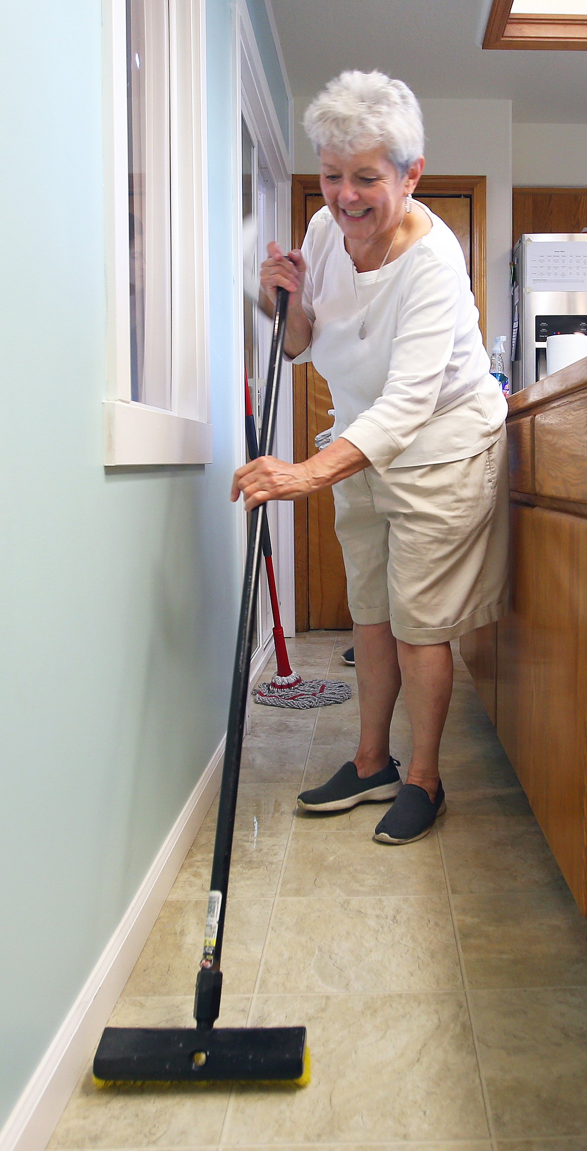 Vicky Houle of Windermere Real Estate scrubs the kitchen floor at Children's Village on Friday.