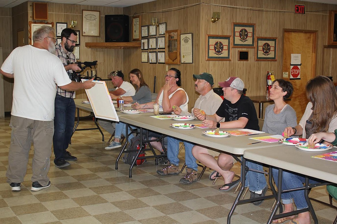 Plains artist Dave Williams shows off a piece of art created by one of the participants in a class last Friday while a videographer from Gray Beard Films in Texas recorded the event for a documentary. (Monte Turner/Valley Press)