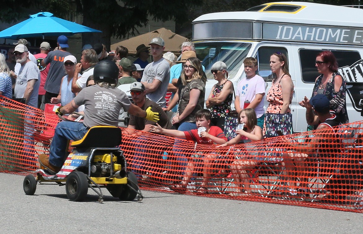 Alex Stafford, 10, of Spirit Lake, receives a high five from one of the drivers Sunday as he and his cousin, KayLynn Rosen, 7, of Coeur d'Alene, enjoy the Big Back-In lawnmower drag races in Spirit Lake.