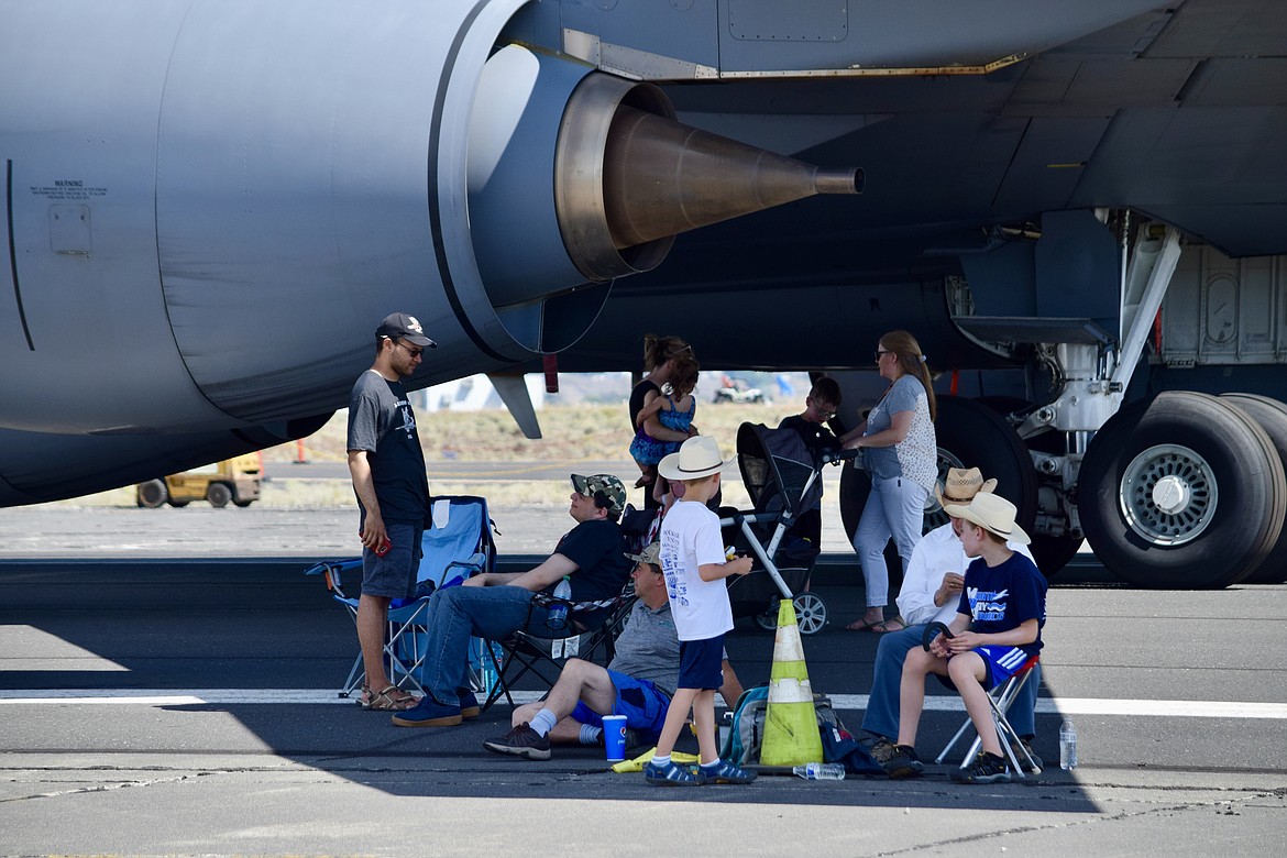 A group of spectators at the 2021 Moses Lake Airshow gather under the shade of a U.S. Air Force KC-135 tanker wing to keep out of the sun.