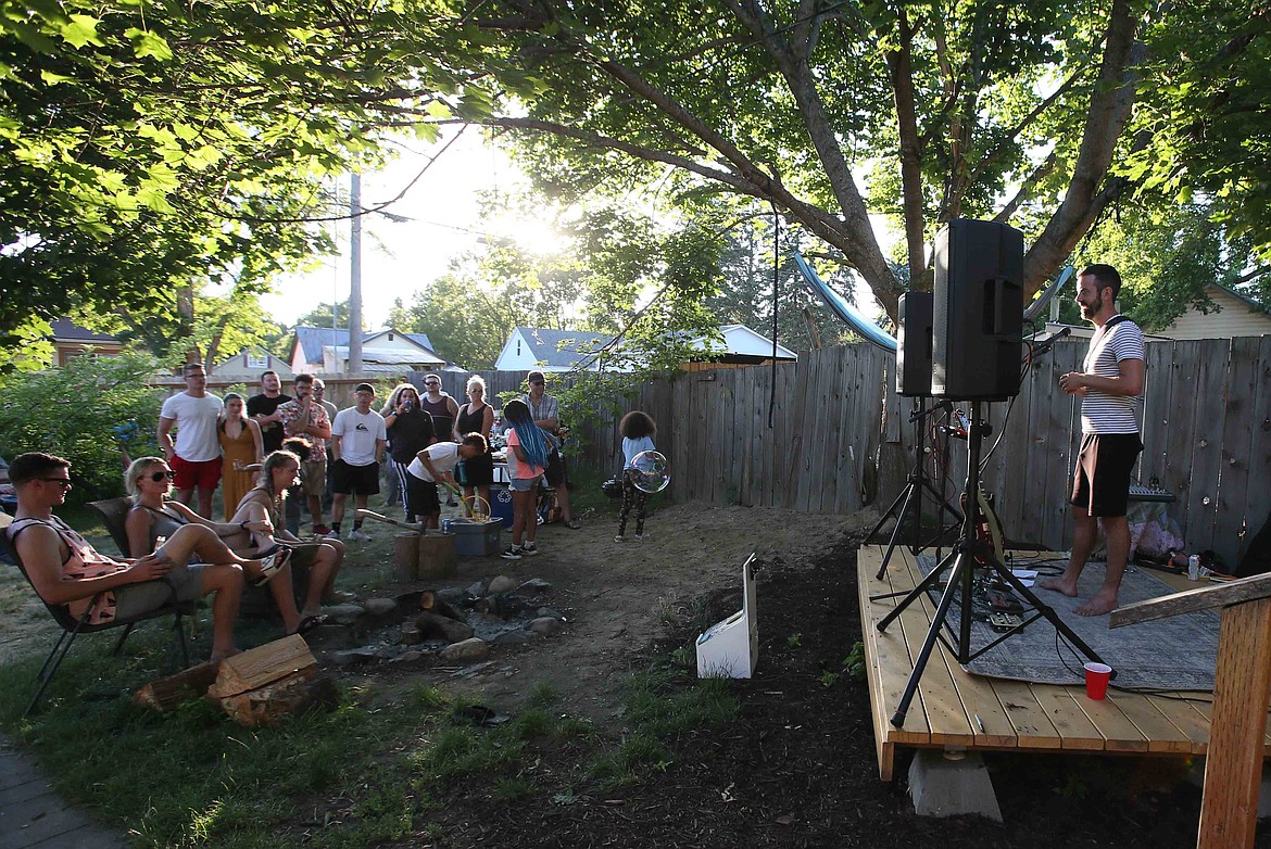 Photographer and keen student of humanity Adam Schluter addresses his guests Monday during a gathering in his back yard. Every other Monday, he welcomes community members to stop by for a meal and live music.