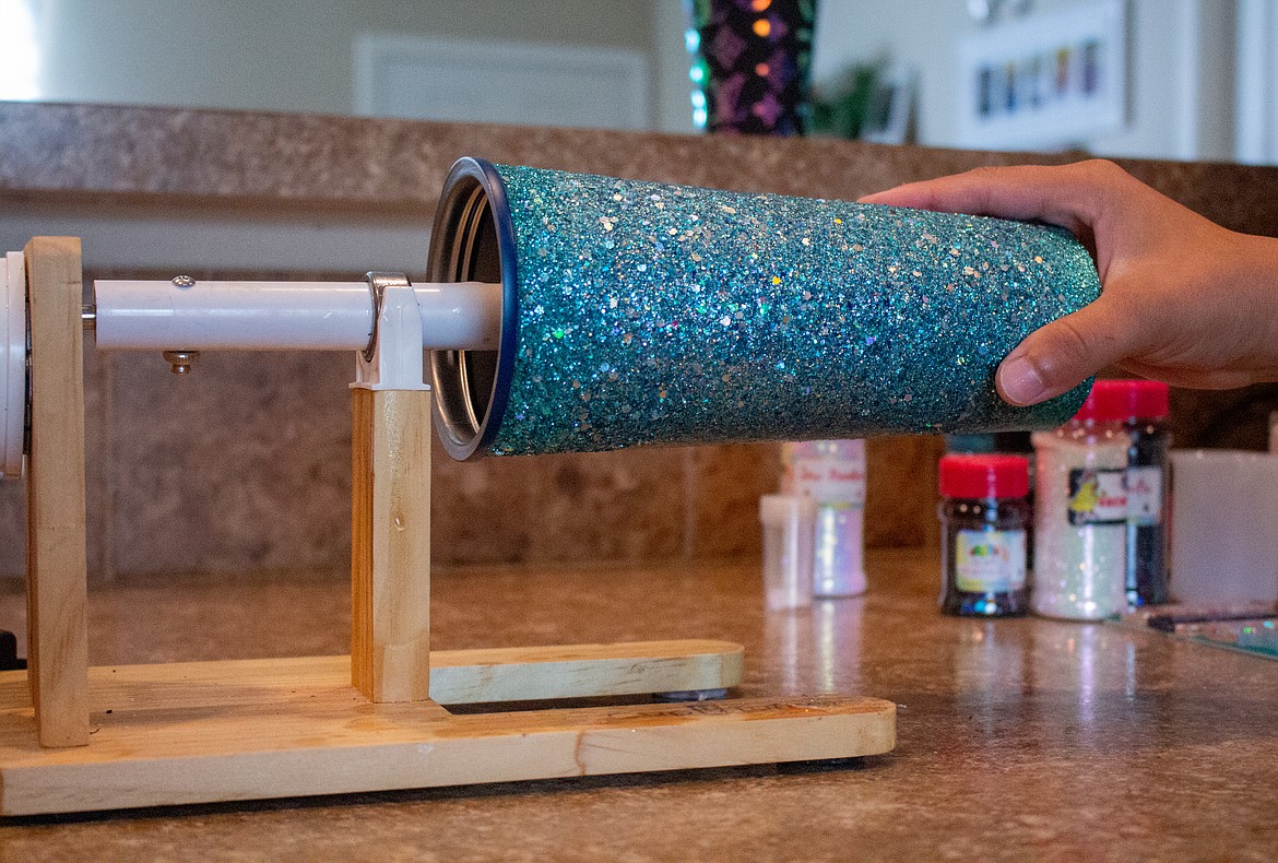 Star Arntson holds a cup on the turning apparatus she uses in her kitchen to make her custom epoxy-coated craft projects.