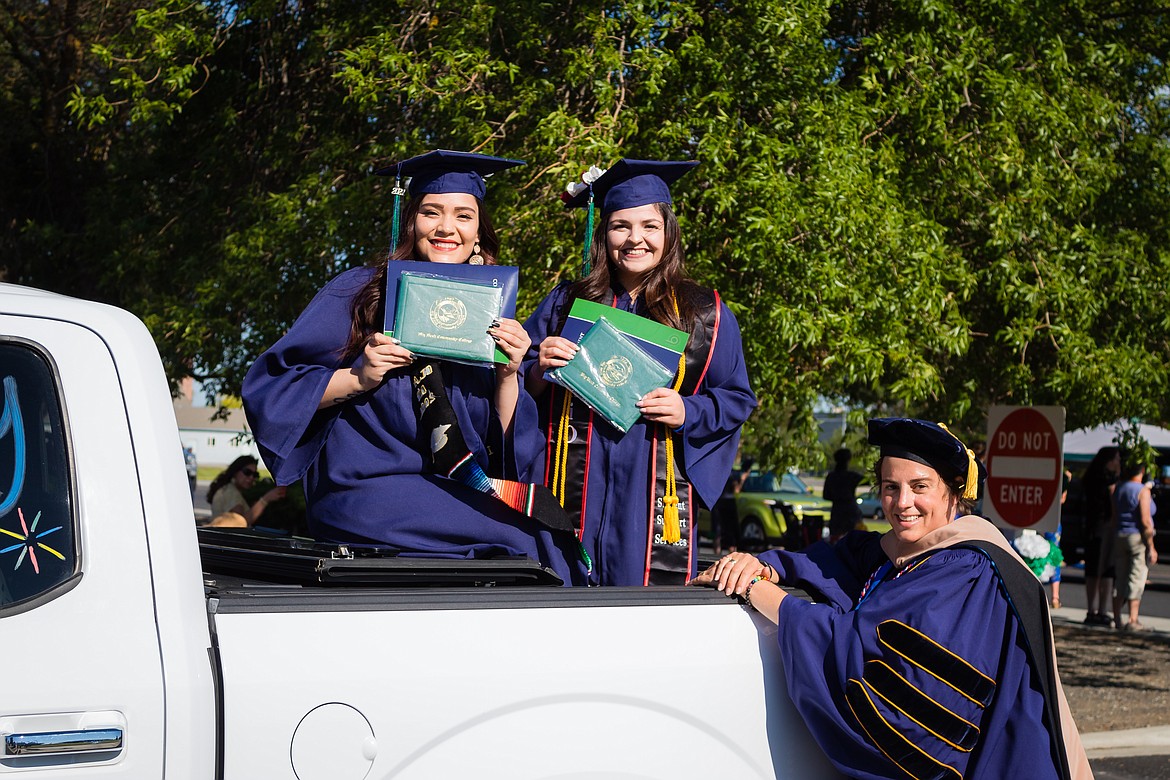 Big Bend Community College President Sara Thompson Tweedy (right) hands out diplomas to two proud BBCC graduates during drive-thru commencement ceremonies June 18.