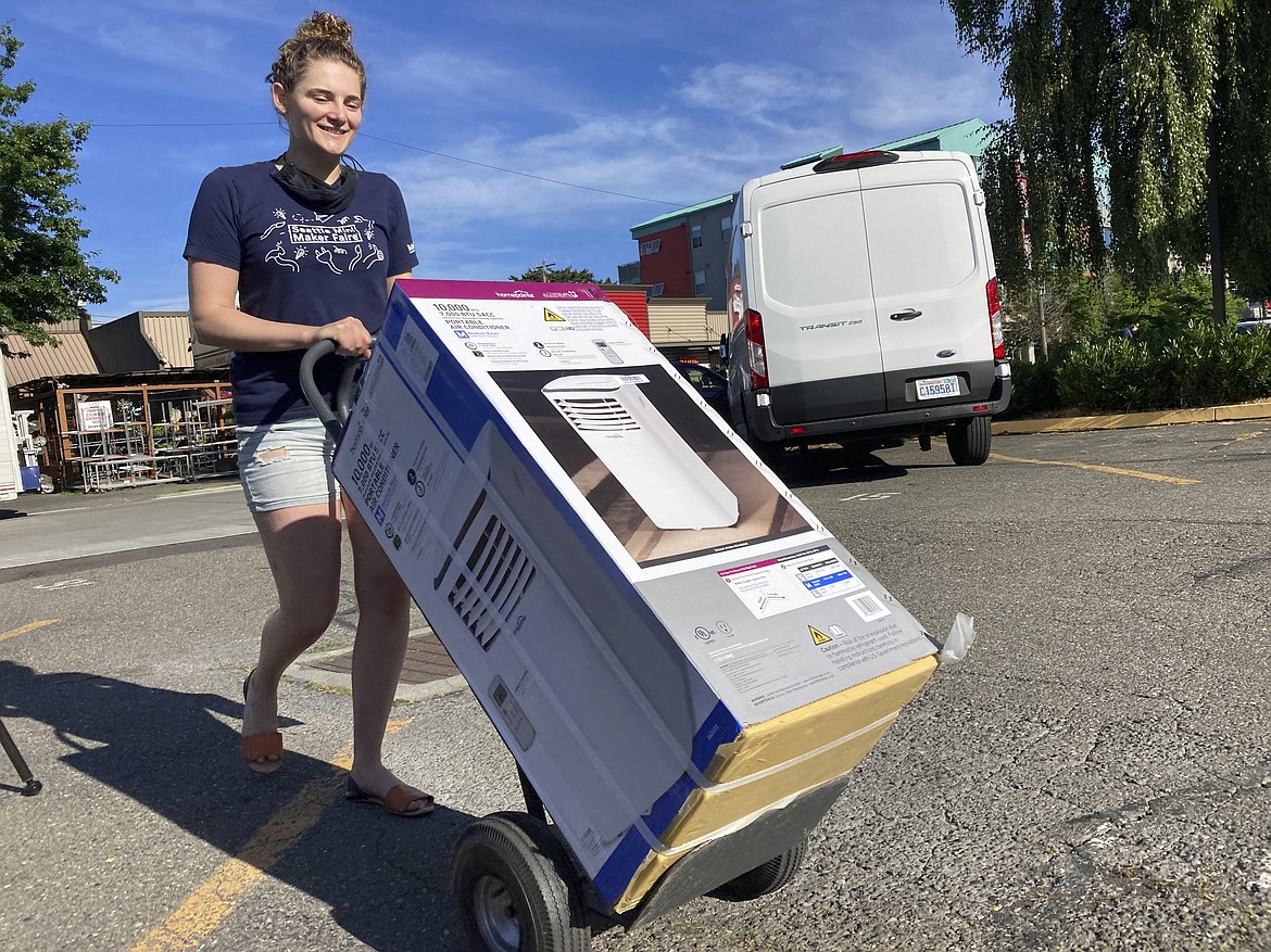 Sarah O'Sell transports her new air conditioning unit to her nearby apartment on a dolly in Seattle on Friday, June 25, 2021. O'Sell snagged one of the few AC units available at the Junction True Value Hardware as Pacific Northwest residents brace for an unprecedented heat wave that has temperatures forecasted in triple-digits. (Manuel Valdes/Associated Press)