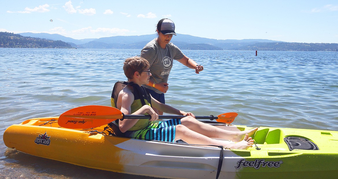 Jenn Skeesick, CAF Idaho regional director, gives a hand to Rhett Owens of Post Falls before he heads out on a kayak at Sanders Beach Friday.