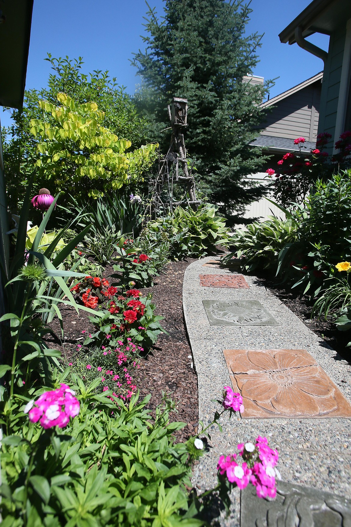 A pathway with intricate stepping stones and lined with brilliant flowers leads to a birdhouse in Susan Lovelace's backyard garden in Hayden.