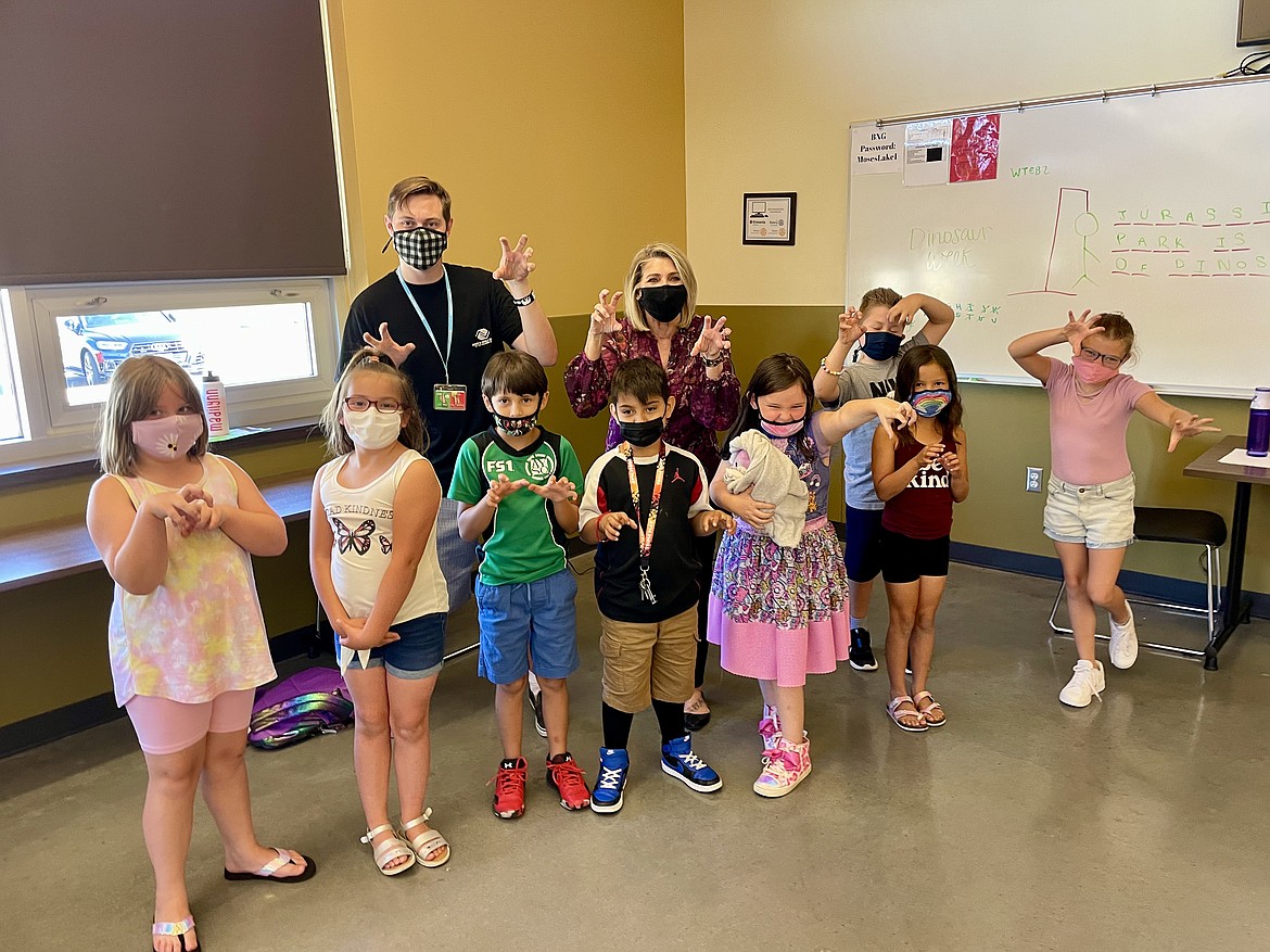 Youth Development Professional Tyler Devereux and Boys & Girls Clubs of The Columbia Basin Executive Director Kim Pope make snarling dinosaur motions with a group of first- and second-graders at the McGraw Family Clubhouse.