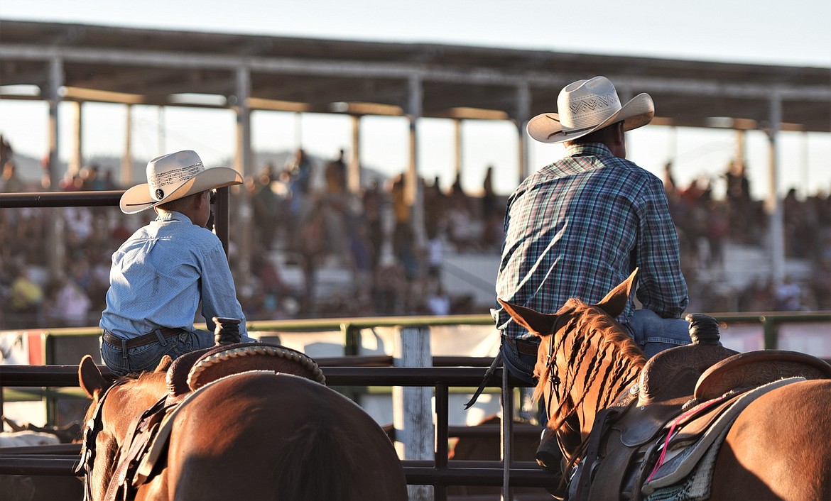 A couple of cowboys enjoy a front-row seat at the Mission Mountain Rodeo. (Scot Heisel/Lake County Leader)