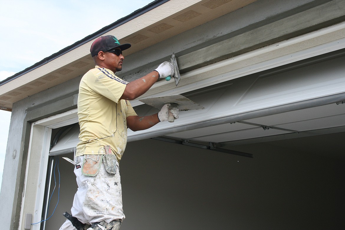 Sergio Infante applies stucco to garage door trim on a house being built in Othello. Finding ways to make it easier to build more housing is the goal of a plan approved by the Othello City Council June 28.