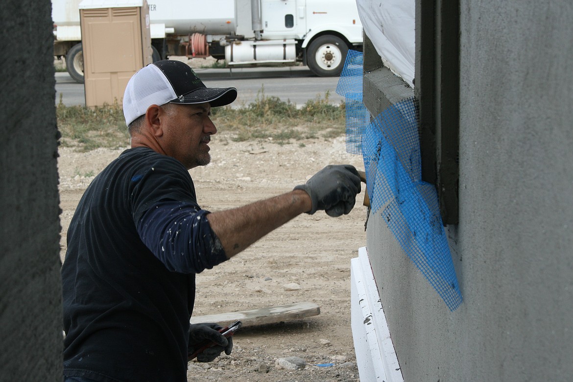 Carlos Gonzalez adds stucco to a windowsill on a house under construction in Othello.