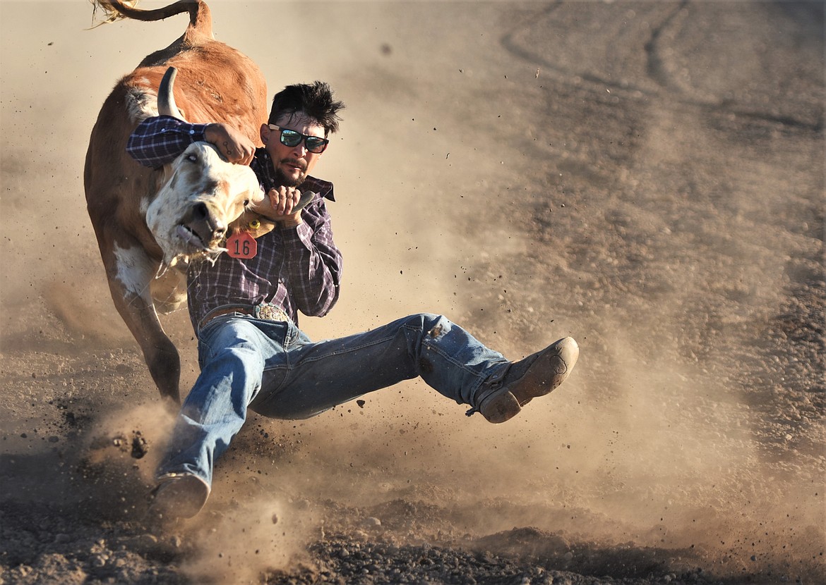 Polson steer wrestler Tyler Houle tries to get his footing during his run Saturday night. (Scot Heisel/Lake County Leader)