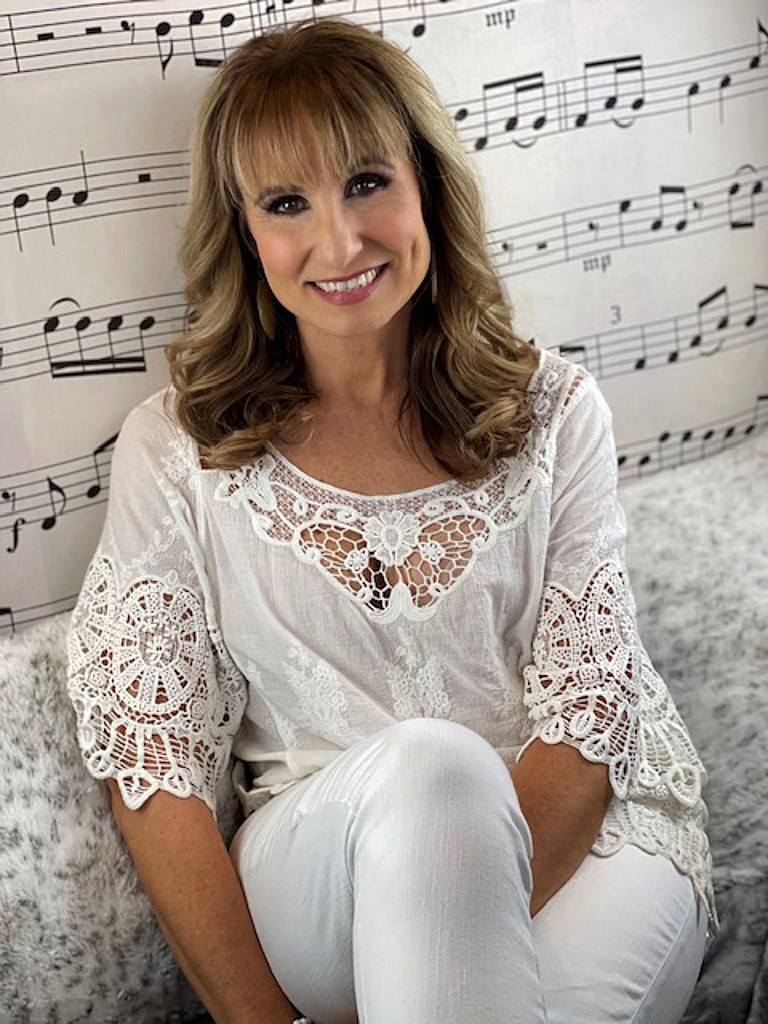 Music notes line the wall behind Debbie Roeber of Moses Lake who sits inside her private voice studio in her home in Moses Lake.