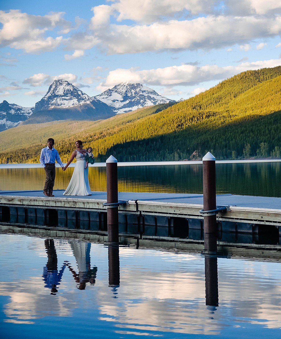 A newlywed couple strolls on a dock on Lake McDonald while eloping in Glacier National Park. (Courtesy of Elope Montana)
