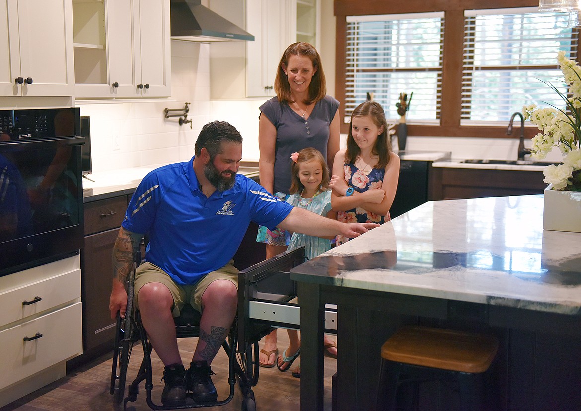 Austin Reese, while his wife Charity and daughters Nadia and Aspen watch, checks out the specially adapted microwave in his new home on Thursday morning. (Heidi Desch/Whitefish Pilot)