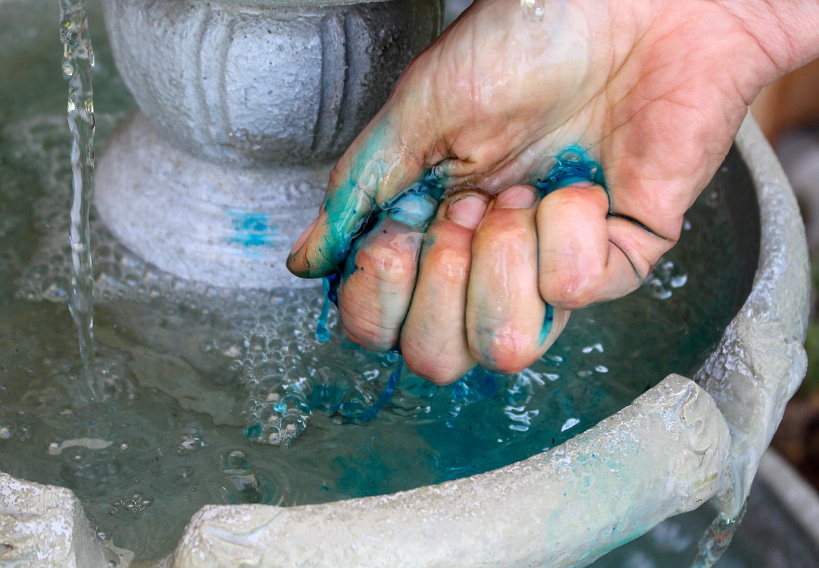 Bobbie Bodenman’s fingers are tinted blue, as she mixes blue food coloring into her fountain water in her backyard in Moses Lake on Thursday.