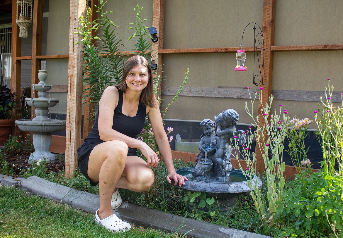 Bobbie Bodenman of Moses Lake kneels between two of her garden fountains in her backyard in Moses Lake on Thursday.