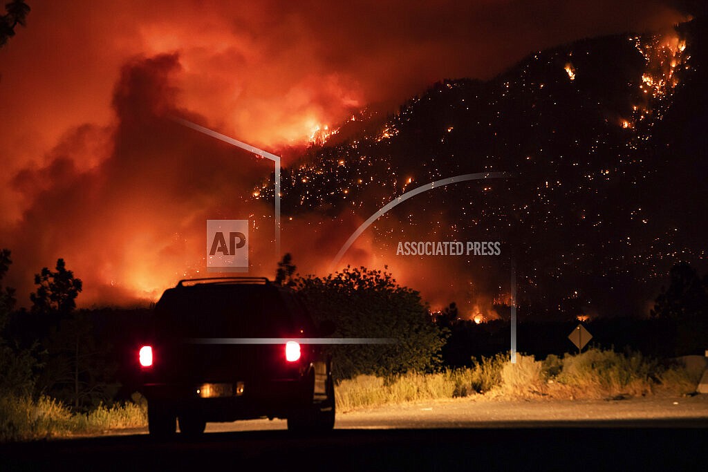 A motorist watches from a pullout on the Trans-Canada Highway as a wildfire burns on the side of a mountain in Lytton, B.C., Thursday, July 1, 2021. (Darryl Dyck/The Canadian Press via AP)