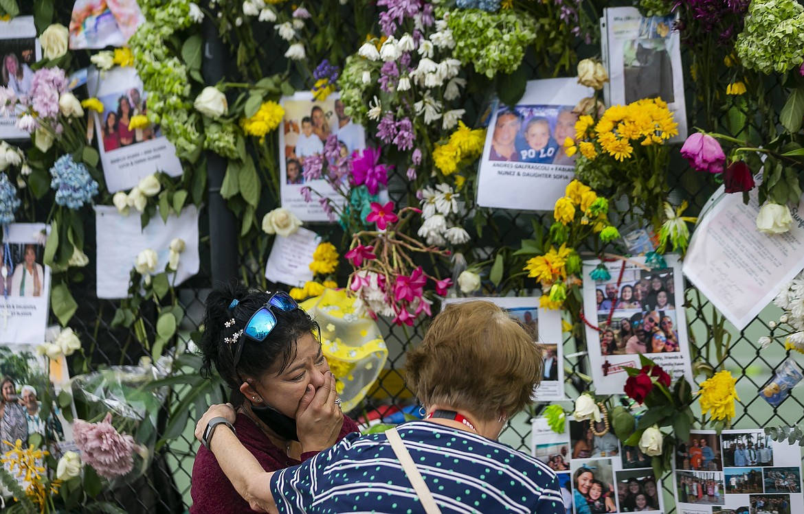 In this June 29, 2021, file photo, mourners visit a makeshift memorial near the site of the collapsed condominium in Surfside, Fla. While hundreds of rescuers search desperately for survivors within the rubble of the collapsed condominium, a smaller cadre of mental health counselors are also deploying to help families and other loved ones cope with the tragedy. (Matias J. Ocner/Miami Herald via AP)