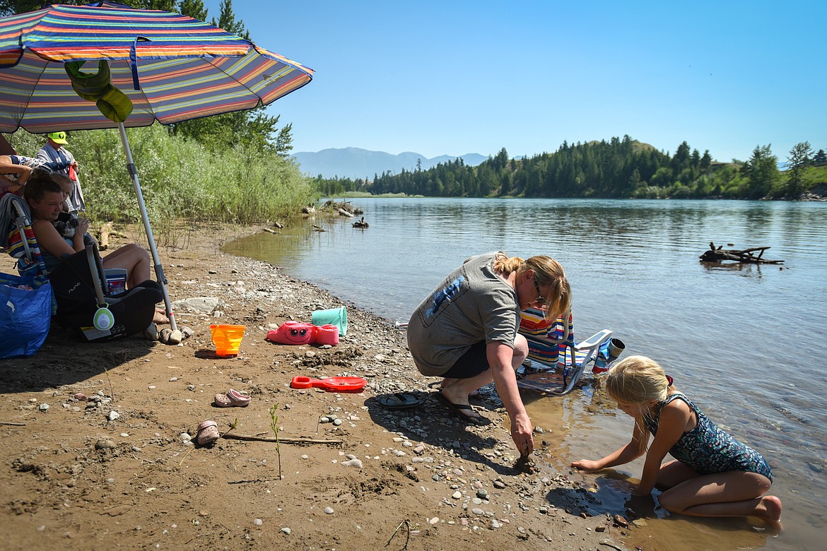 Evelyn Rhoades, right, builds tiny sand castles along the Flathead River with her grandmother, Wendy Derouin, center, and mother Chantel Rhoades, left, on Tuesday, June 29. (Casey Kreider/Daily Inter Lake)