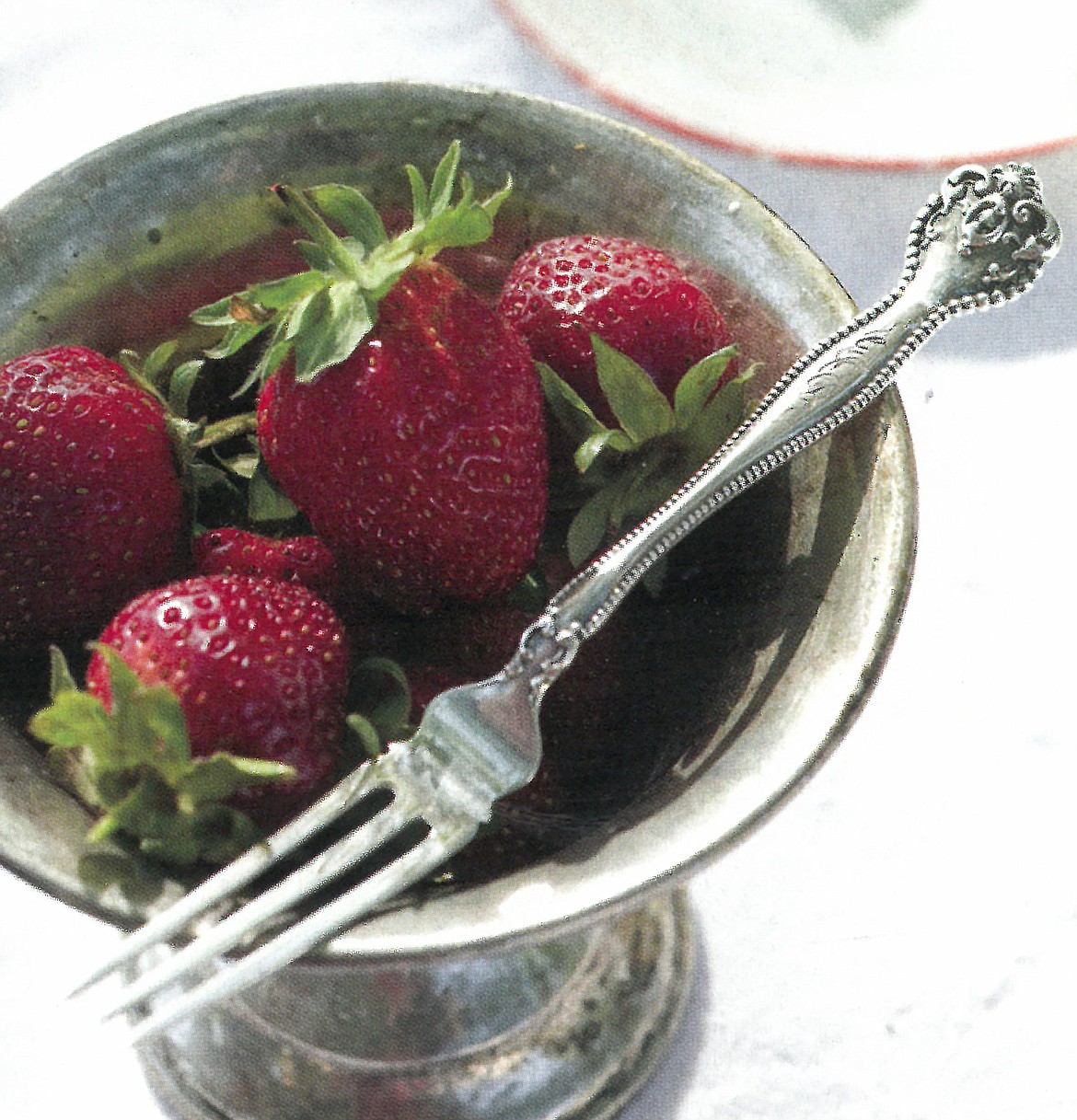 Chilled whole strawberries are a classic treat served with an elegant vintage strawberry fork.