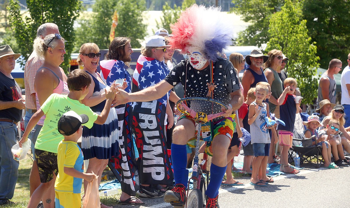 Clown Bill Landwehr slaps hands with spectators he rides a bike in the Bayview Daze parade Saturday