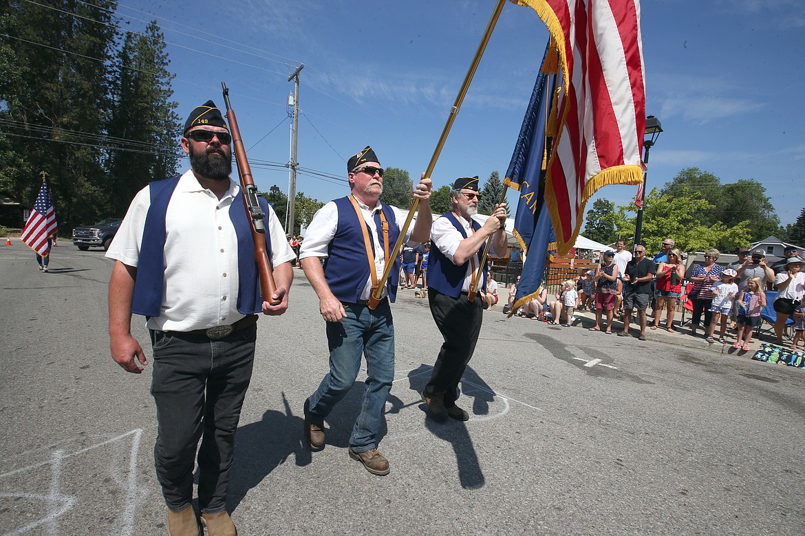 Veteran Michael Pickhinke, center, carries the American flag and is joined by Jake Erwin and Leonard Hoener as they march up Maine Street in the Spirit Lake Fourth of July parade on Sunday.