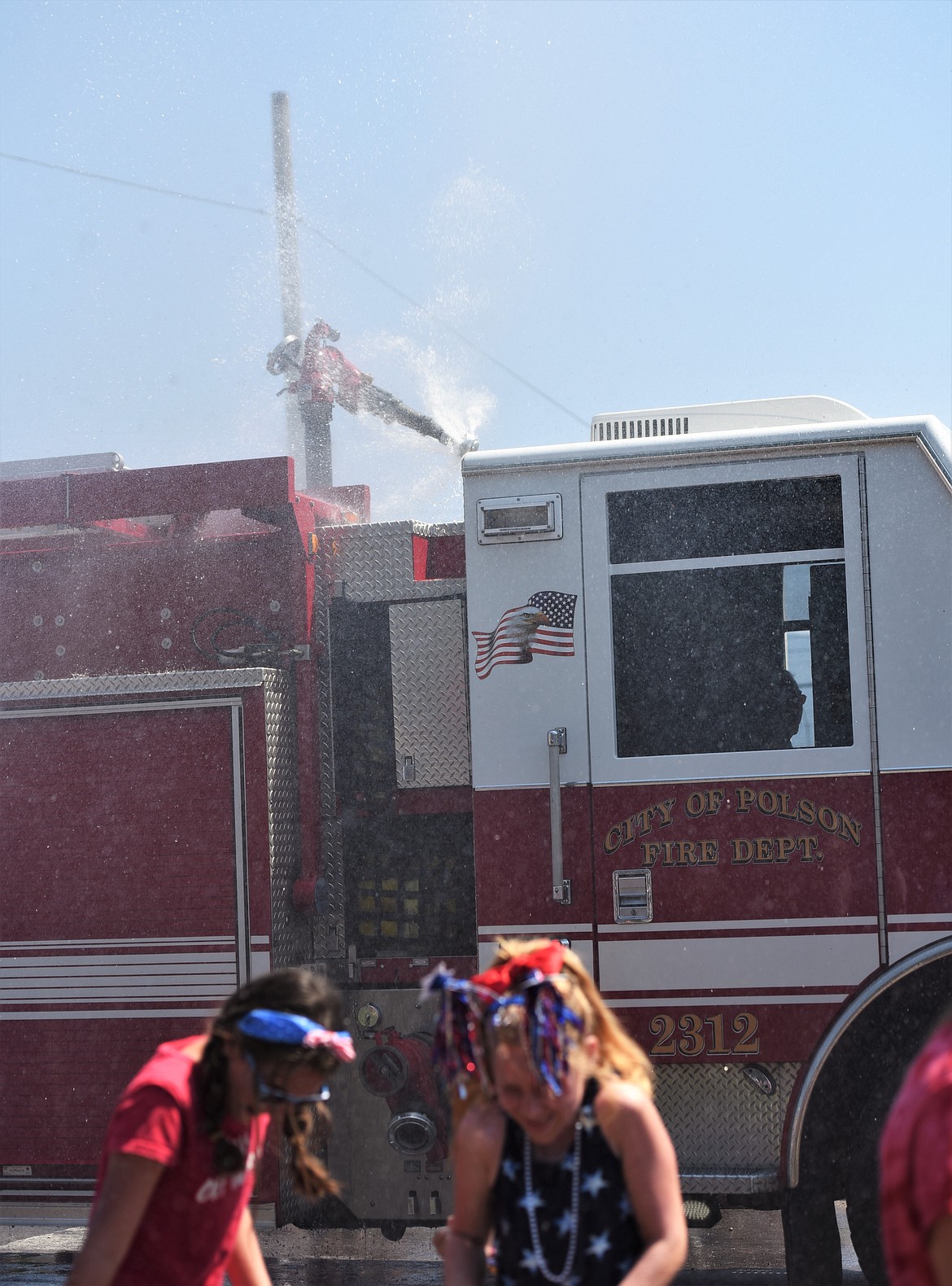 The Polson Fire Department cools off the crowd with a spray of water. (Scot Heisel/Lake County Leader)