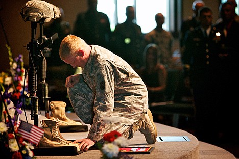 Spc. Tristan Nielsen kneels at the gear of Sgt. Nathan R. Beyers and Spc. Nicholas W. Newby during their memorial service Saturday as he gives his final salute to his fellow soldiers and friends who died July 7 in Iraq.