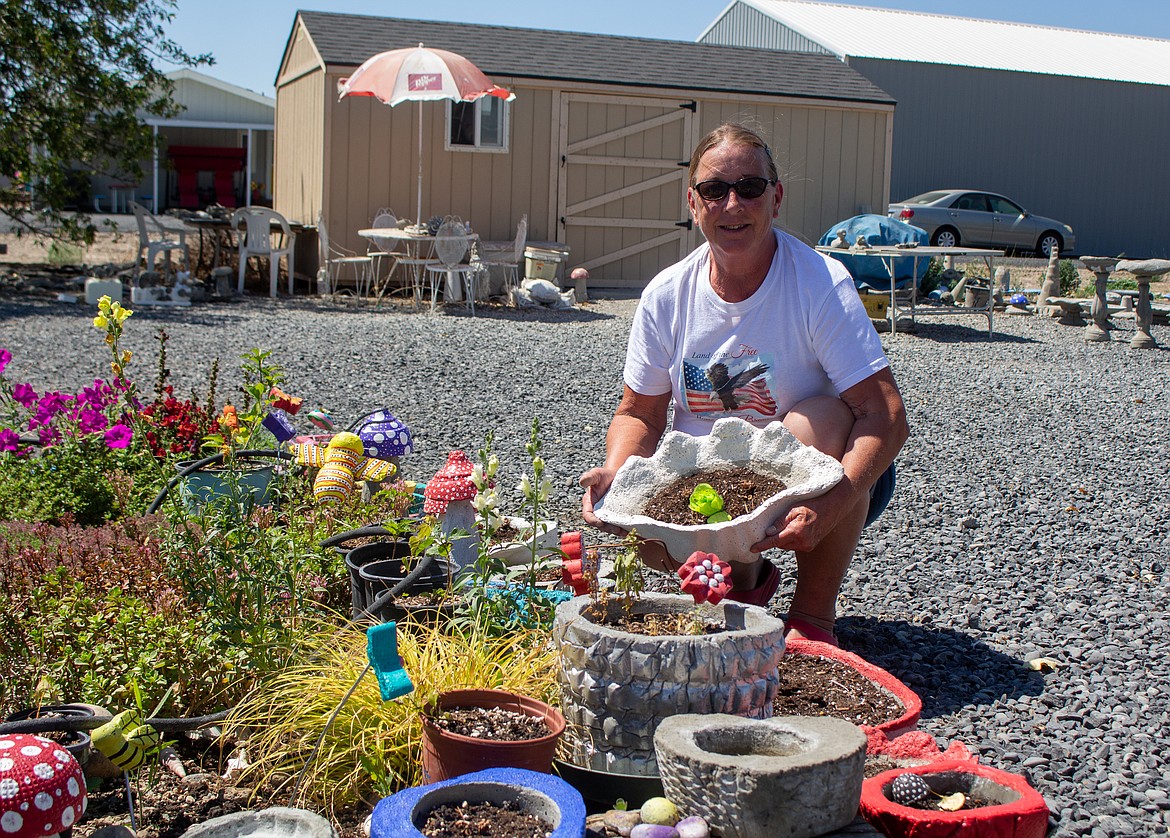 Joan Lewis holds up one of her custom-crafted planters behind her home in Moses Lake on Wednesday.