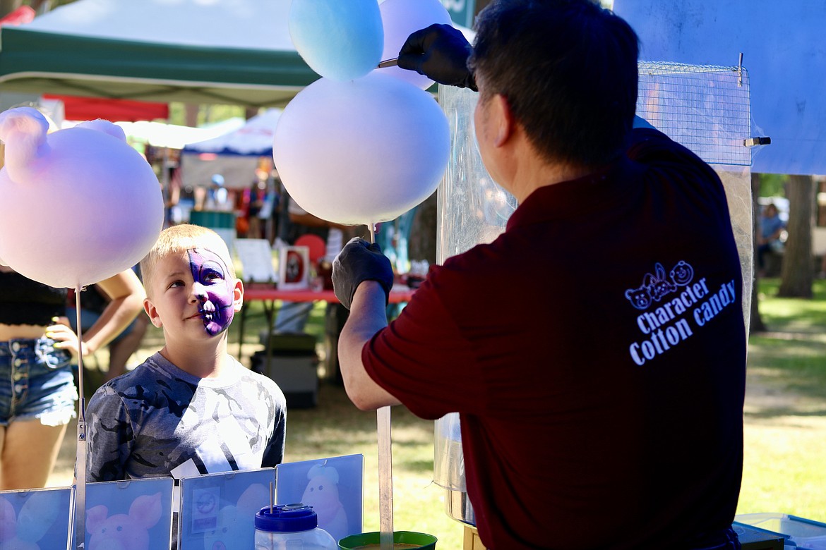Aarow Goldsmith, 8, from North Spokane watches as Steve Chong, owner of the Character Cotton Candy stand, creates a cotton candy character during the Post Falls Festival at Q'emilm Park on Friday. HANNAH NEFF/Press