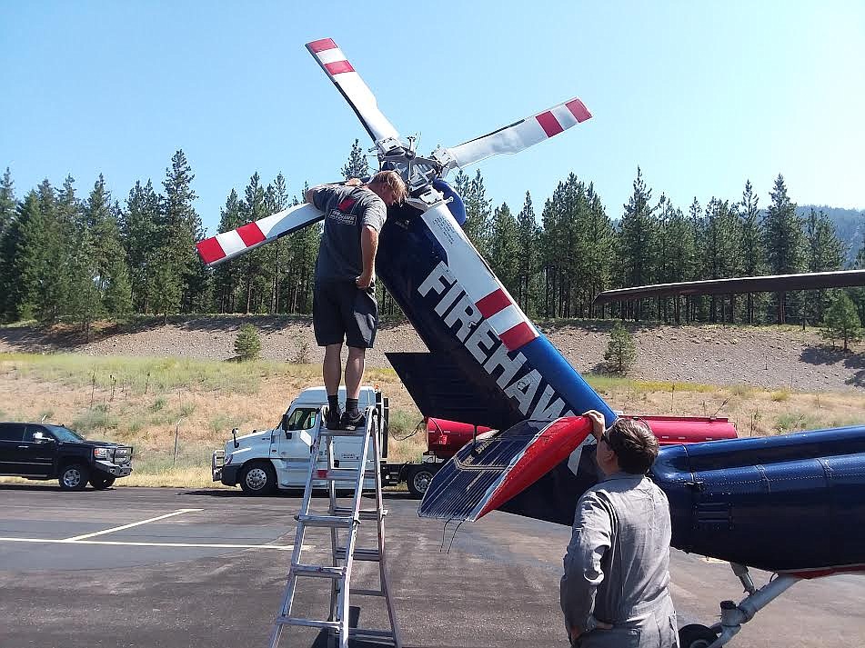 Two crew members work on the tail rotor of one of seven Blackhawk helicopters last Friday at the Superior County Airport. The team came from the National Interagency Fire Center in Boise, Idaho. (Monte Turner/Mineral Independent)
