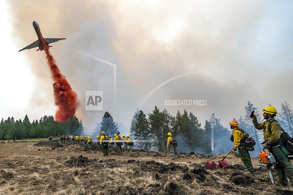 Wildland firefighters watch and take video with their cellphones as a plane drops fire retardant on Harlow Ridge above the Lick Creek Fire, southwest of Asotin, Wash., Monday, July 12, 2021. The fire, which started last Wednesday, has now burned over 50,000 acres of land between Asotin County and Garfield County in southeast Washington state. (Pete Caster/Lewiston Tribune via AP)