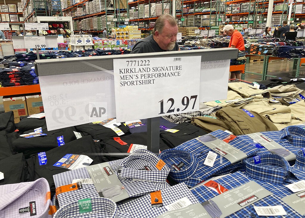 A sign displays the price for shirts as a shopper peruses the offerings at a Costco warehouse on Thursday, June 17, 2021, in Lone Tree, Colo. American consumers faced a third straight monthly surge in princes in June, the latest sign that a rapid reopening of the economy is fueling a pent-up demand for goods and services that in many cases remain in short supply. (AP Photo/David Zalubowski)