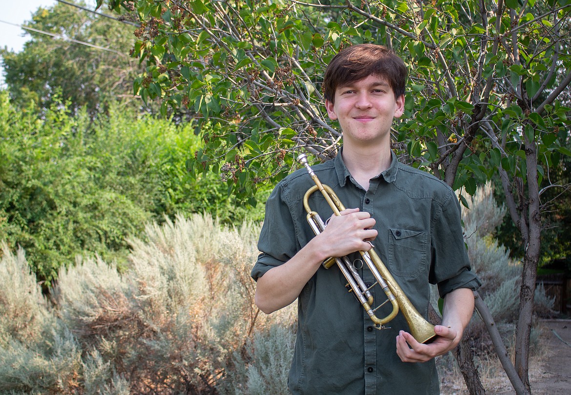 Nathan Fisher holds his trumpet in his arms while standing in the backyard of his family’s home in Moses Lake on Tuesday.