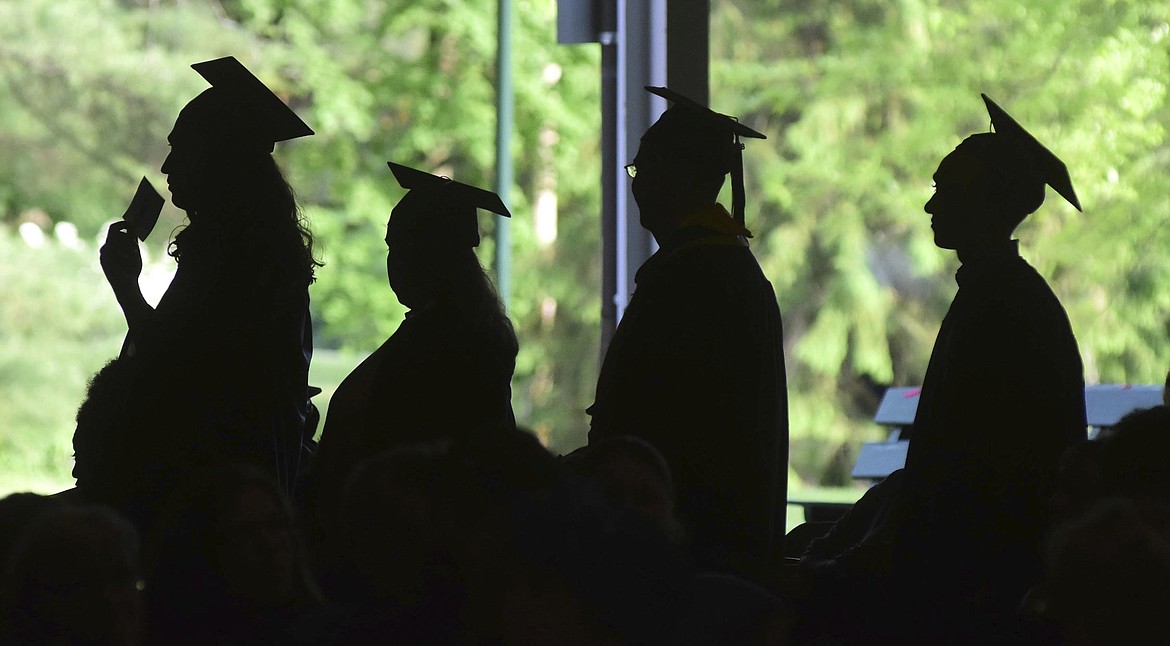 Graduates are silhouetted against the green landscape as they line up to receive their diplomas at Berkshire Community College's commencement exercises at the Shed at Tanglewood in Lenox, Mass., June 1, 2018.