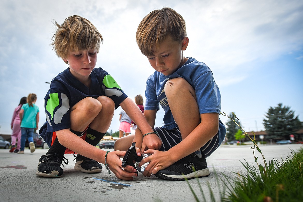 Stetson Morris, left, and Charley Duffey work on removing a letter written in chalk with a spray bottle during a summer school exercise at Muldown Elementary School in Whitefish on Tuesday, July 13. (Casey Kreider/Daily Inter Lake)