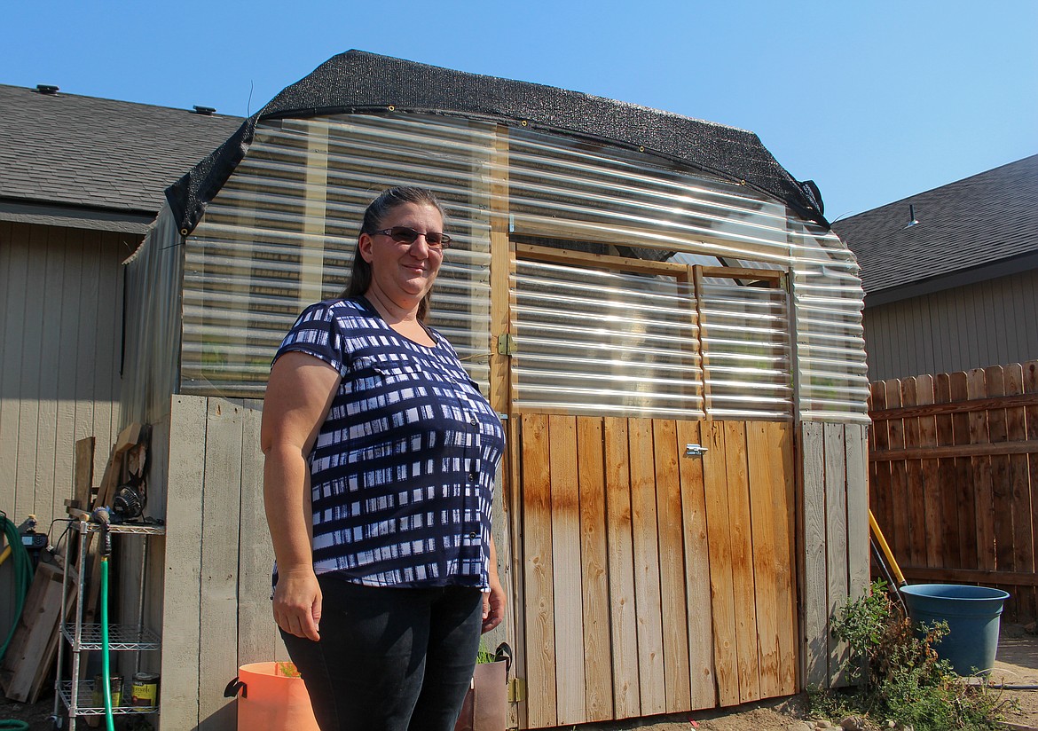 Stephanie Suarez, of Moses Lake, stands next to her greenhouse behind her home.