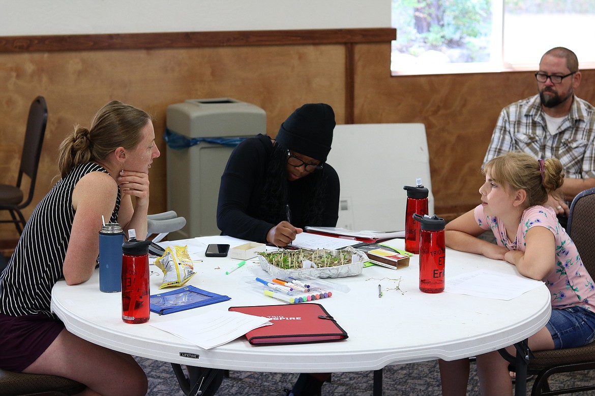 Kayla Bordelon, left, a doctoral student at U of I, walks middle school students Mahala Regis, center, and Erika Crowe through building their own forest with matches at the week-long environmental science field program in Q’emiln Park in Post Falls on Thursday.On the far right is Randy Palmer with TRIO. HANNAH NEFF/Press