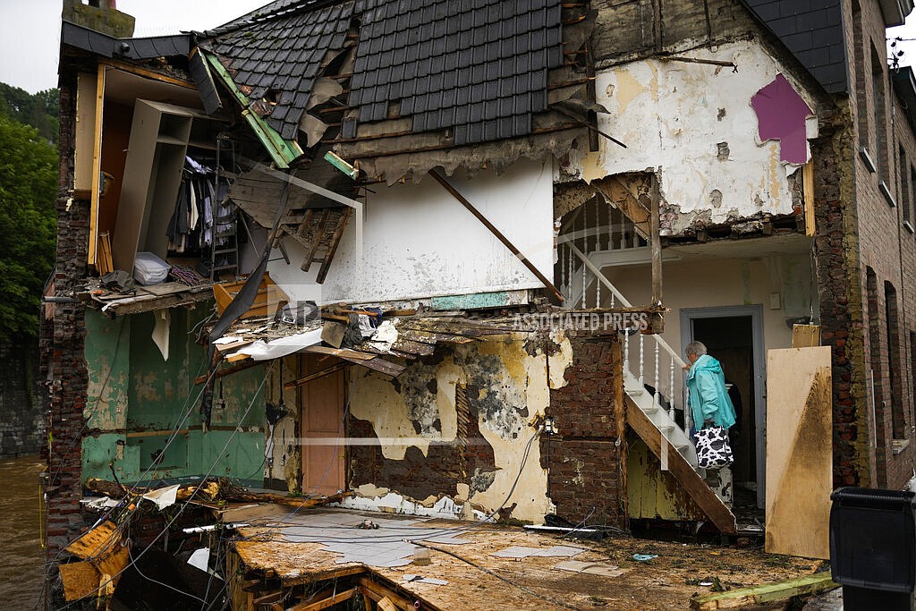 A woman walks up the stairs in her damaged house after flooding in Ensival, Vervier, Belgium, Friday July 16, 2021. Severe flooding in Germany and Belgium has turned streams and streets into raging torrents that have swept away cars and caused houses to collapse. (AP Photo/Francisco Seco)