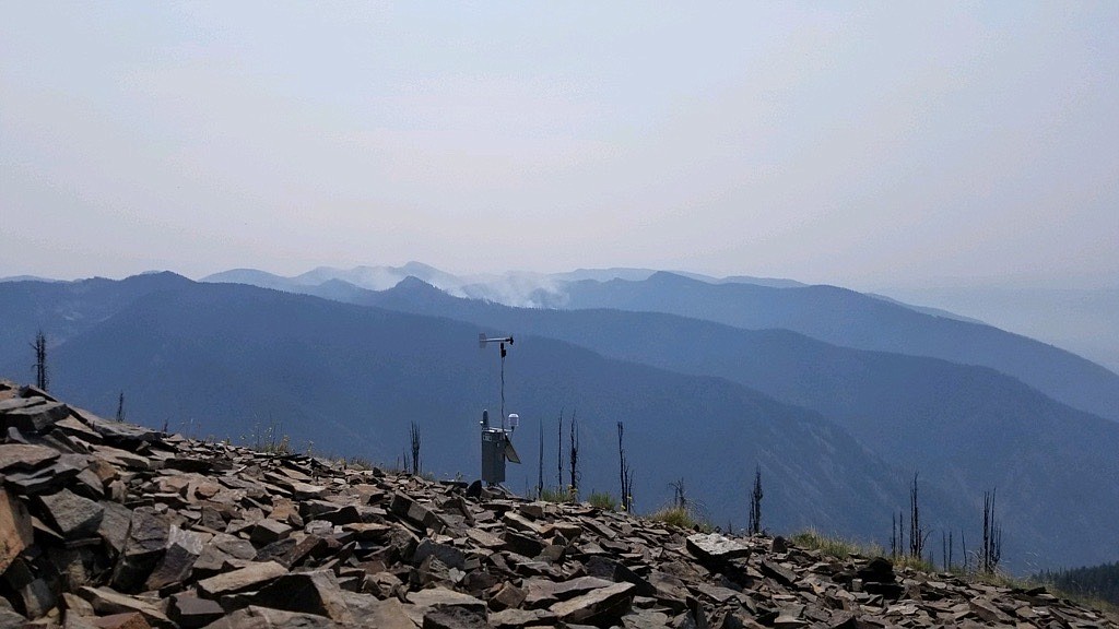 The Remote Automatic Weather Station at Cougar Peak Lookout in Sanders County helps fire officials gauge what a fire may do. In the background, smoke drifts from the Thorne Creek and Winniemuck fires. The fires grew together recently and have been burning slowly in extremely steep and rugged terrain northeast of Thompson Falls. (U.S. Forest Service photo)